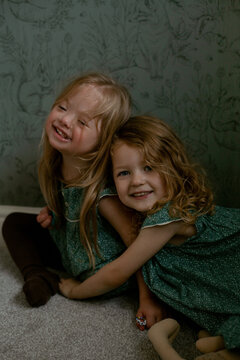 Twin girls with Down Syndrome hugging each other and smiling