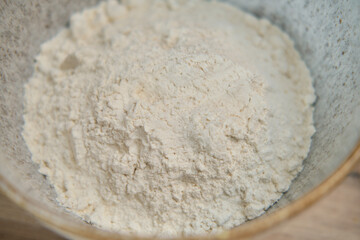 Fototapeta na wymiar Flour in a white ceramic bowl, close - up view from above