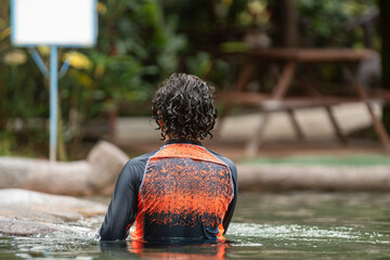 Joven adolescente disfrutando dentro de una piscina térmica natural  del volcán Arenal - obrazy, fototapety, plakaty