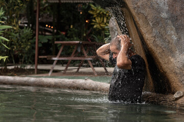 Hombre adulto mayor disfrutando y dándose un baño en una piscina natural de aguas termales 