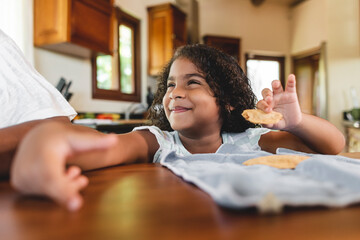 Hermosa niña afroamericana con una linda sonrisa comiendo en la mesa de su casa