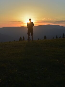 man stands at sunset and looks at the landscape