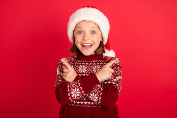 Photo of little girl happy positive smile point fingers empty space ad promo advise christmas season isolated over red color background