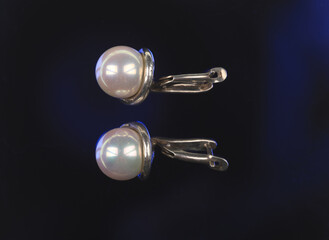 silver earrings with pearl isolated on black background