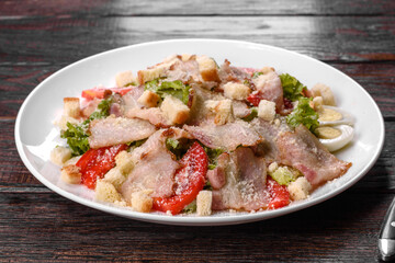 Delicious fresh salad with bacon and tomatoes with spices and greens