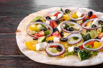 Tasty fresh Greek salad on a pita cooked for a festive table