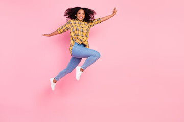 Fototapeta na wymiar Photo of cheerful inspired lady jump have fun wear plaid shirt jeans sneakers isolated pink color background