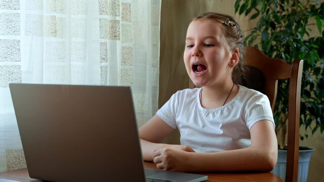 Speech training concept. Little girl uses a laptop to study at home with a teacher, a speech therapist. Distance learning. A kid doing exercises for correct pronunciation.