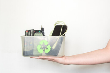 Una mano sosteniendo una caja de plástico transparente con el símbolo del reciclaje que contiene...