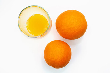 Top view of a ripe oranges and a glass of fresh squeezed orange juice on white background. © Luka