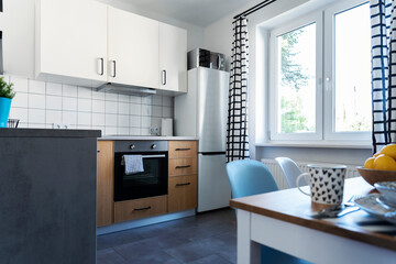 Interior of kitchen with cabinets, dining table and window and curtains. Cozy kitchen in apartment in modern deisgn.