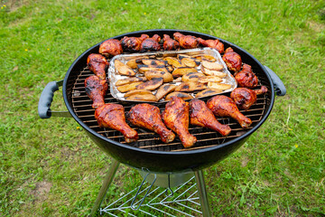 Chicken legs and sliced potatoes baked on a grill - 459549769