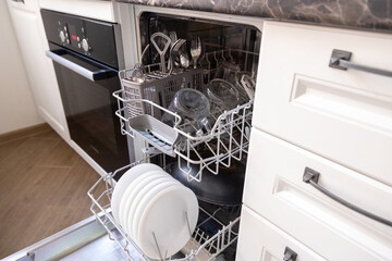the dishwasher is filled with dishes, the door is open. kitchen furniture.