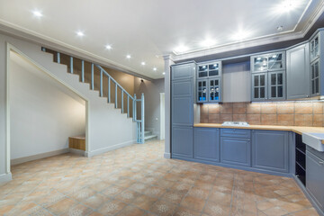 Spacious kitchen. the facade of the headset is made in blue. The lamps are located along the perimeter of the ceiling. Interior of a cottage or townhouse