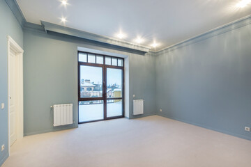 A large room in blue tones, unfurnished, with a panoramic window with a beautiful view. Interior of a cottage or townhouse