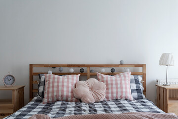 Interior of bedroom with comfortable bed with sheets in grid and pink pillows. Cozy rest room with...