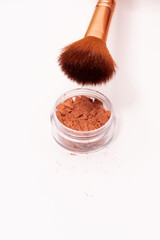 Creative photo of cosmetic swatches. Broken eye shadows in bronze colour and make up brush on a white background 