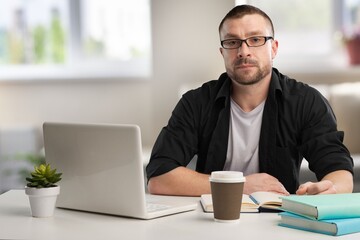 Smiling mature businessman with laptop sitting in office.