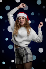 cheerful latin girl celebrating christmas with a santa hat and a background with defocused lights, space for text