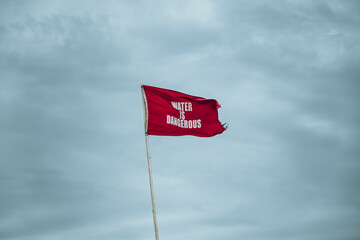 a red flag of lifeguard station warning that water is dangerous against the grey and overcast sky at the Atlantic coast in the united states