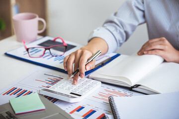 business woman or accountant who are using a calculator to calculate business data Accounting documents and laptop computer at the office business idea