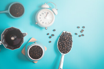 top view of black coffee and coffee beans with alarm clock on blue background
