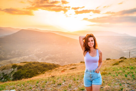 Beautiful slender woman on top of a mountain at sunset. Amazing landscape with a gradient of mountains. The concept of sports and active life.