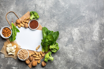Obraz na płótnie Canvas Concept: Purchase healthy clean food. Protein source for vegetarians: vegetables, nuts and legumes top view on a concrete background with a paper bag and a white notebook for a list of products.