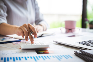 Fototapeta premium business woman or accountant who are using a calculator to calculate business data Accounting documents and laptop computer at the office business idea