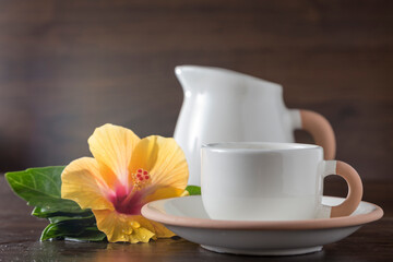 cups and milk jug next to a hibiscus flower