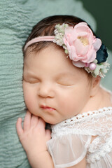 Fototapeta na wymiar Newborn girl on a green background. Photoshoot for the newborn.. A portrait of a beautiful, newborn baby girl 
