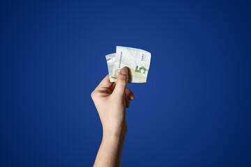  Hand holding a 5 Euro bill isolated on blue background