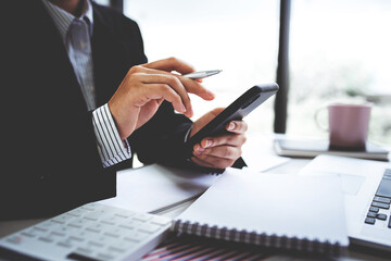 Businesswoman or accountant using the phone to check business information. Accounting Documents and Laptop at Small Office Business Ideas