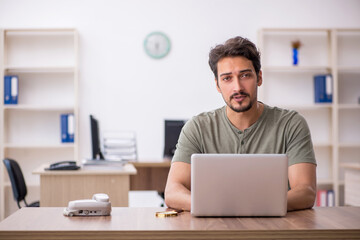 Young male employee sitting at workplace