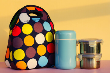 snack on a break with a lunchbox. colorful handbag, blue thermos and two metal containers with food. lunch for a schoolboy or an office worker