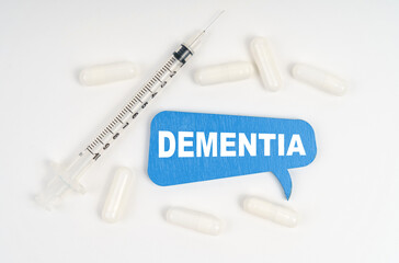 On a white background pills, a syringe and a blue plate with the inscription - DEMENTIA