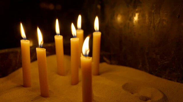 Candles in sand lit from confession in church