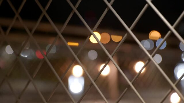 Close up chain link fence bokeh color lights in background