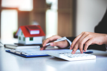 Fototapeta premium A young woman's hand presses a calculator to determine and summarize the cost of mortgage home loans for refinancing plans, lifestyle concepts.