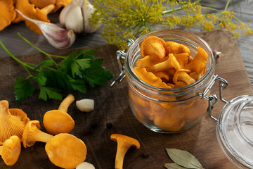 Preserving chanterelle mushrooms in a jar with spices and herbs. Pickling wild edible mushrooms - obrazy, fototapety, plakaty