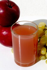 glass of juice and fruits apples and grape in the white background