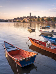 six fishing boats on lake Bolsena and view to city Marta in Italy - obrazy, fototapety, plakaty