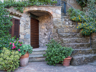 Fototapeta na wymiar old stone house and flowers around stair and wooden door