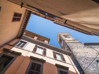 Fototapeta na wymiar low angle view to roofs and tower with clock in italian city