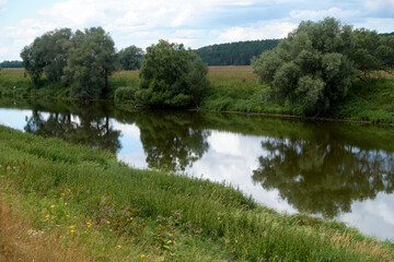 Fototapeta na wymiar Beautiful calm river on a summer day. Reflection of trees in the river. Protva river, Russia.