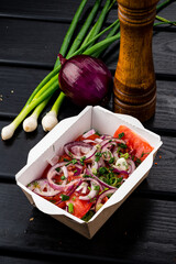 salad of fresh vegetables tomatoes, onions and cucumbers in a takeaway box