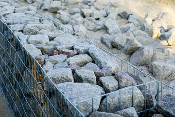 unfinished gabion fence wall construction from steel mesh with stones