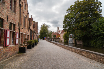 Fototapeta premium Kopfsteinpflaster Straße neben Fluss in historischer Stadt, Brugge in Belgien, Stadtkern