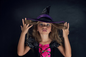 A girl dressed as a witch and a wide-brimmed hat for Halloween.