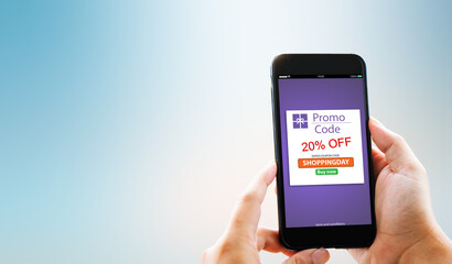 Online Discount coupon promotion code concept.Hands holding mobile phone